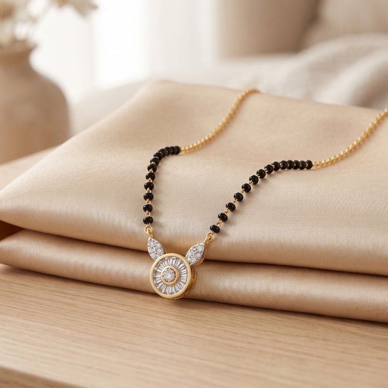 A gold-tone necklace with a circular pendant and black bead accents, displayed on folded beige satin fabric over a light wood surface.
