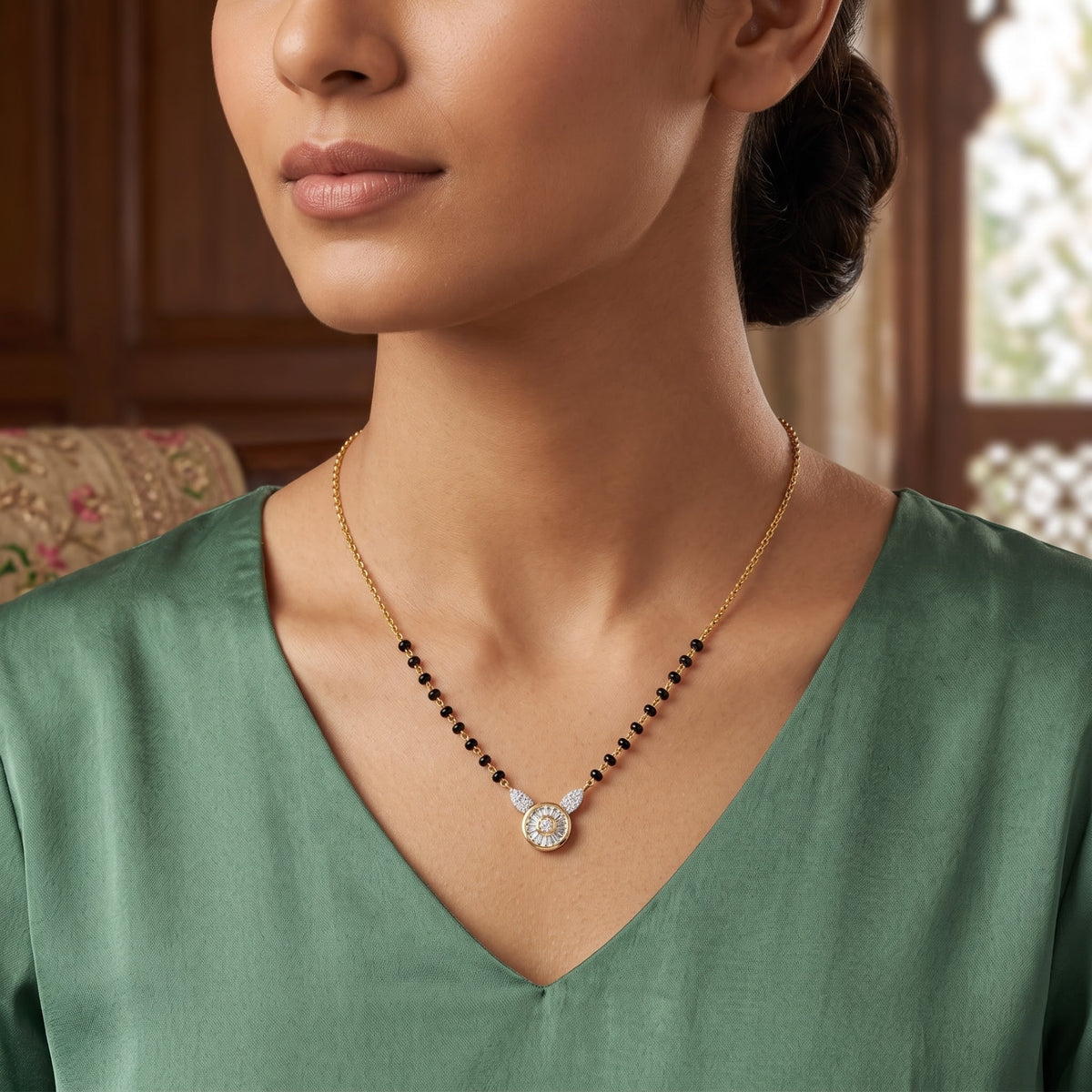 A close-up lifestyle shot of a model wearing a delicate gold necklace with a winged pendant featuring a central clear gemstone and small side stones, accented by a row of small black beads along the chain.
