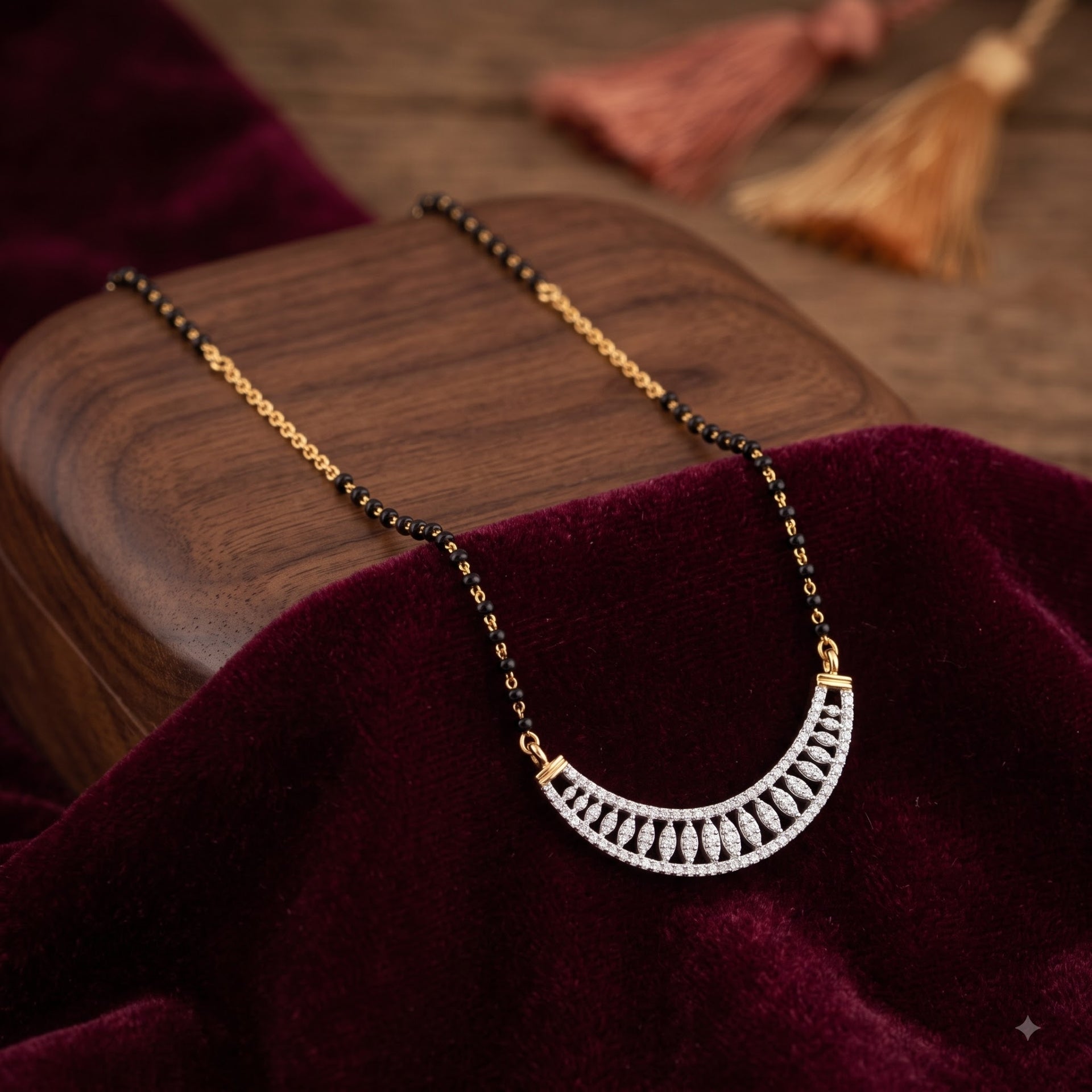 A gold and black beaded necklace with a silver crescent-shaped pendant set with clear stones, displayed on a dark wooden block draped with deep burgundy velvet.