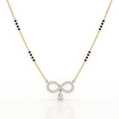 A gold chain necklace featuring a central infinity symbol pendant paved with clear stones and a dangling clear teardrop stone, with small black bead accents along the chain, shown on a white background.