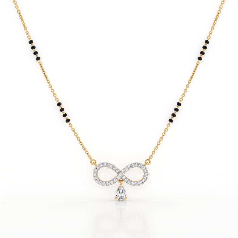A gold chain necklace featuring a central infinity symbol pendant paved with clear stones and a dangling clear teardrop stone, with small black bead accents along the chain, shown on a white background.