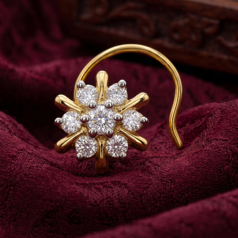 A gold flower-shaped hoop nose ring with clear gemstones, displayed on a textured dark red velvet fabric.