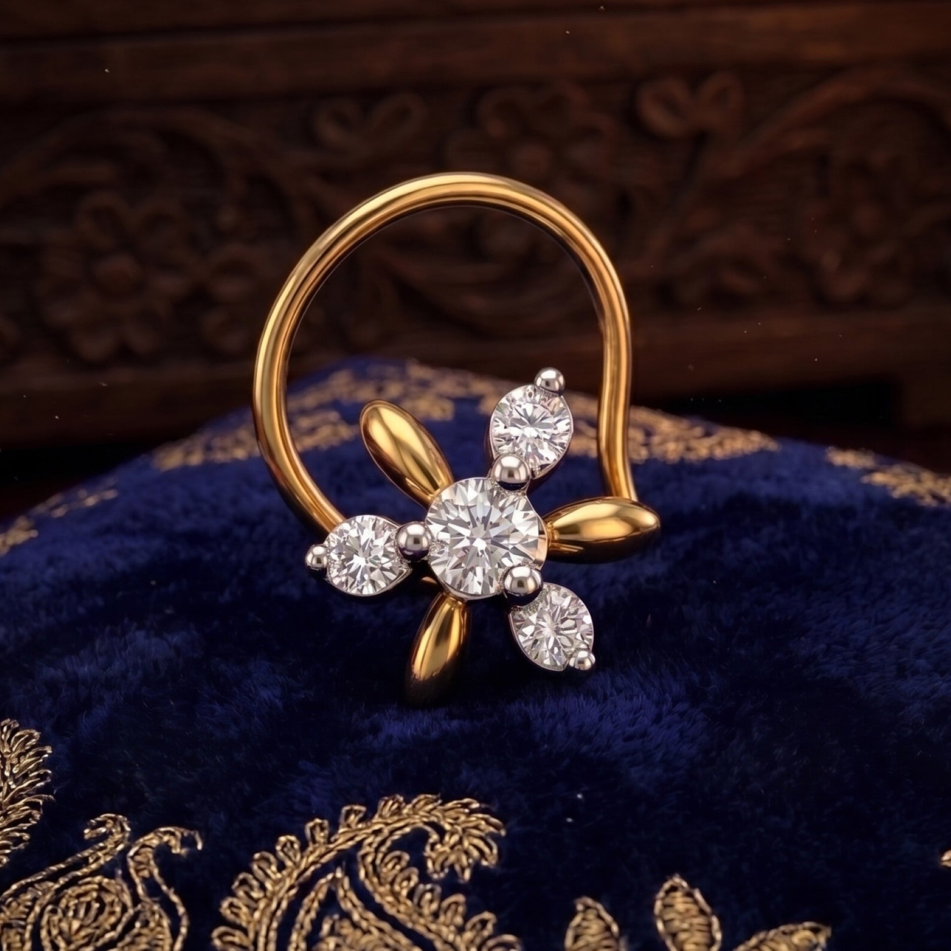 A gold and silver-tone flower-shaped nose ring with a large round center stone and three smaller accent stones, displayed on a dark blue velvet fabric with gold embroidery.
