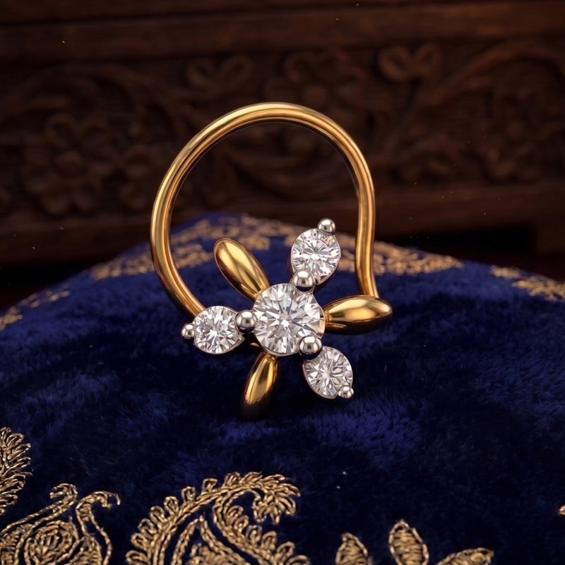 A gold and silver-tone flower-shaped nose ring with a large round center stone and three smaller accent stones, displayed on a dark blue velvet fabric with gold embroidery.