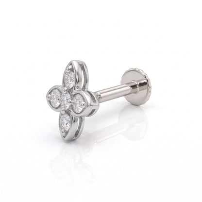 A silver-toned four-petal flower stud nose ring with clear gemstones, shown from an angled side view on a white reflective background.