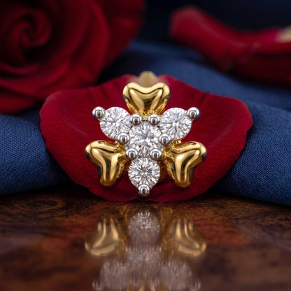 A gold and white diamond snowflake ring displayed on a red rose petal with a blue fabric background.