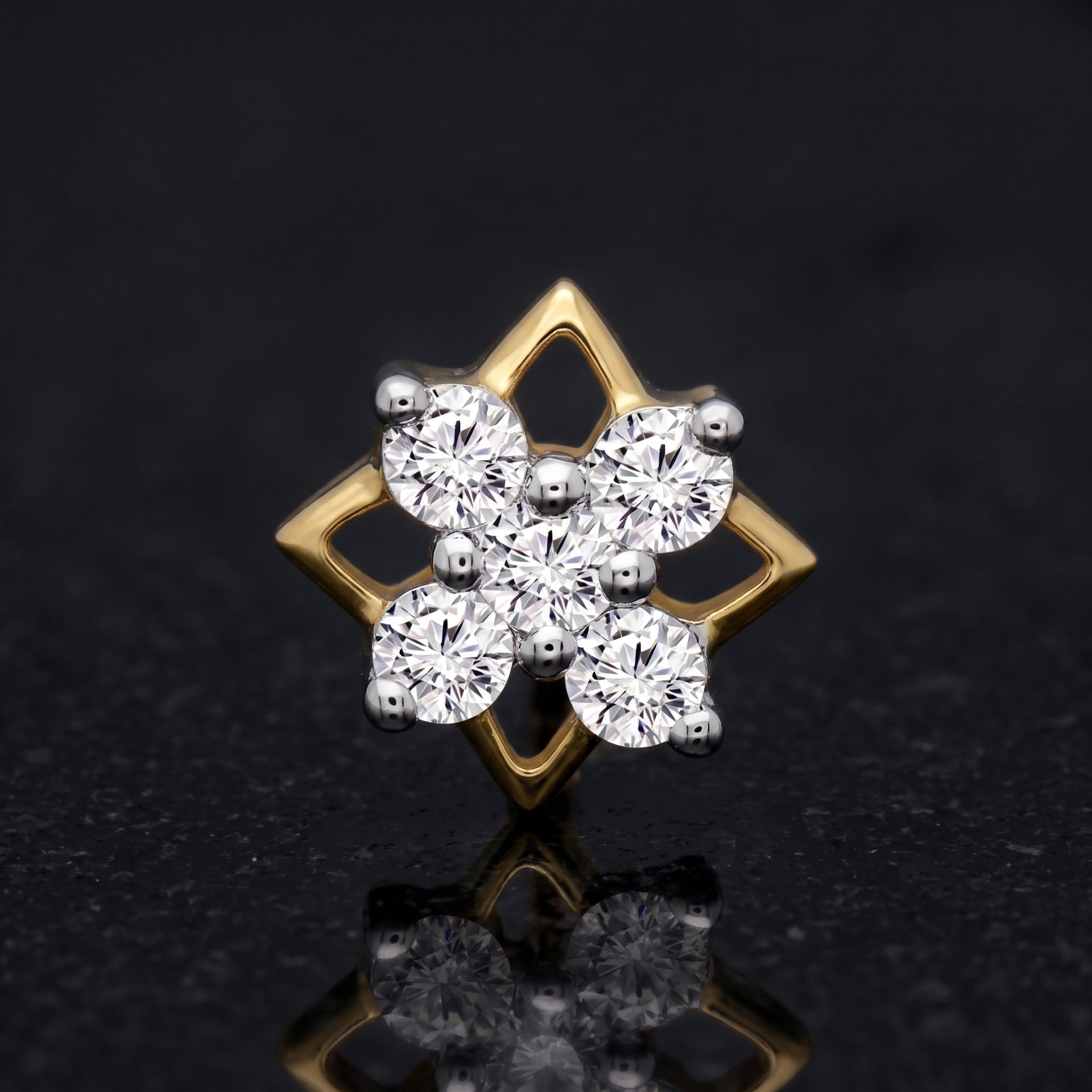 A gold and silver-tone diamond cluster stud nosepin featuring a six-petal floral design with round-cut clear stones, set against a dark reflective background.