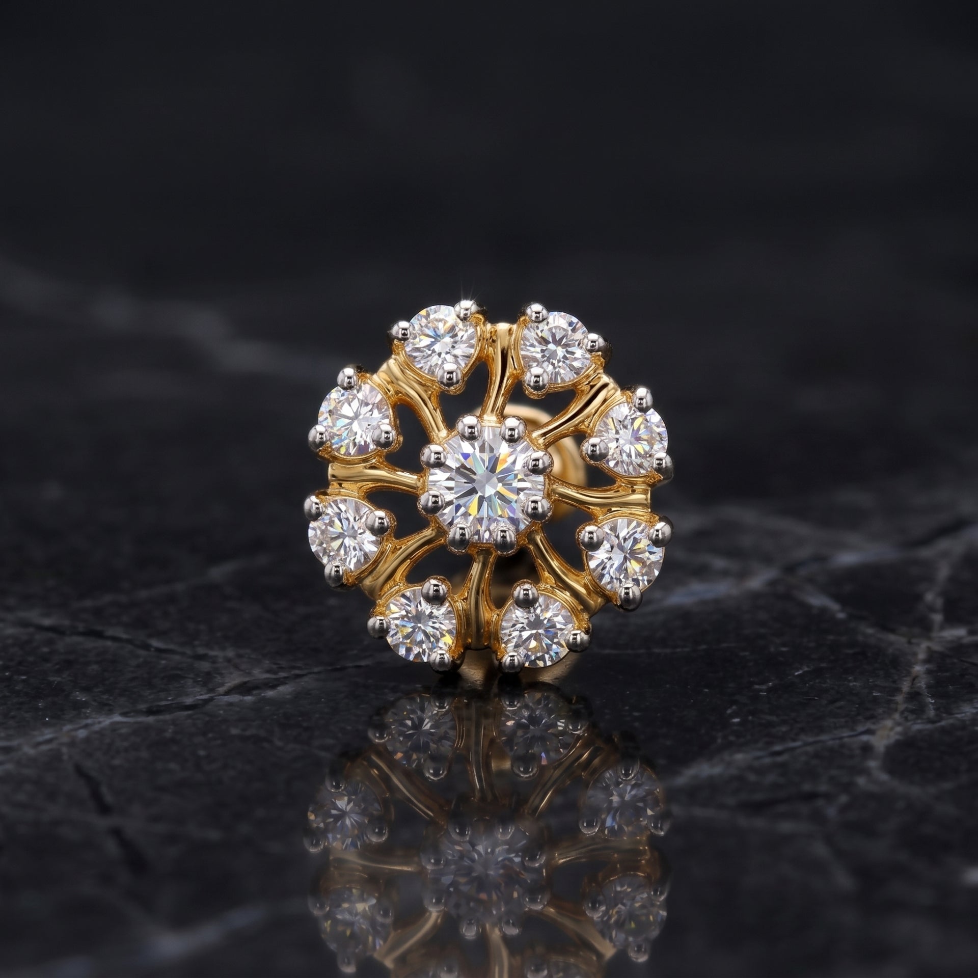 A gold flower-shaped ring with a central round diamond and surrounding smaller diamonds, displayed on a dark reflective surface.