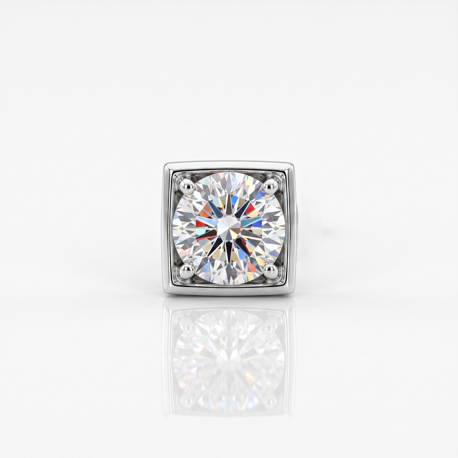 A square-cut diamond solitaire ring in a silver-toned metal setting, centered on a clean white background with a soft reflection below.