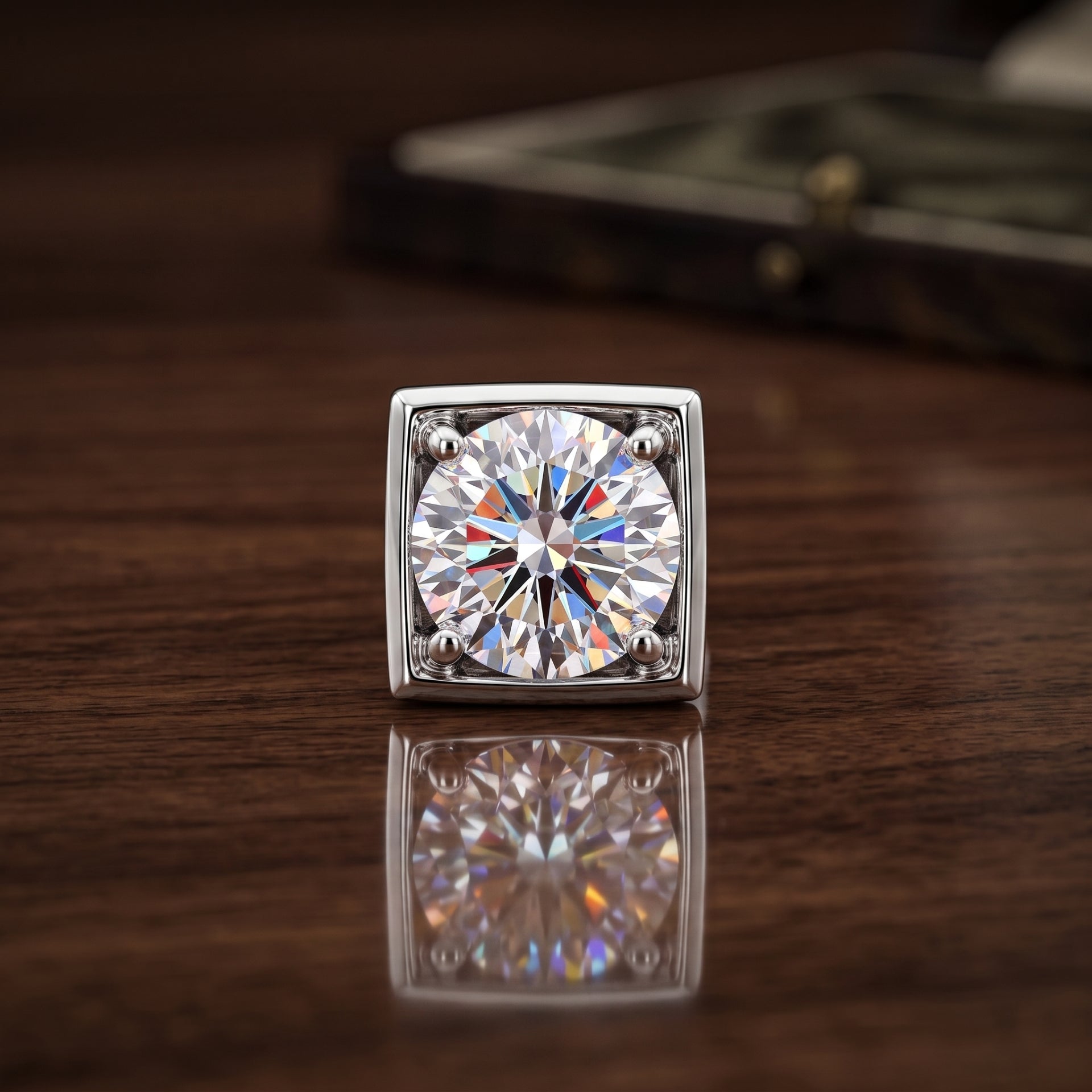 A square solitaire ring with a brilliant-cut clear gemstone in a silver-toned setting, resting on a polished dark wood surface with its reflection visible below.