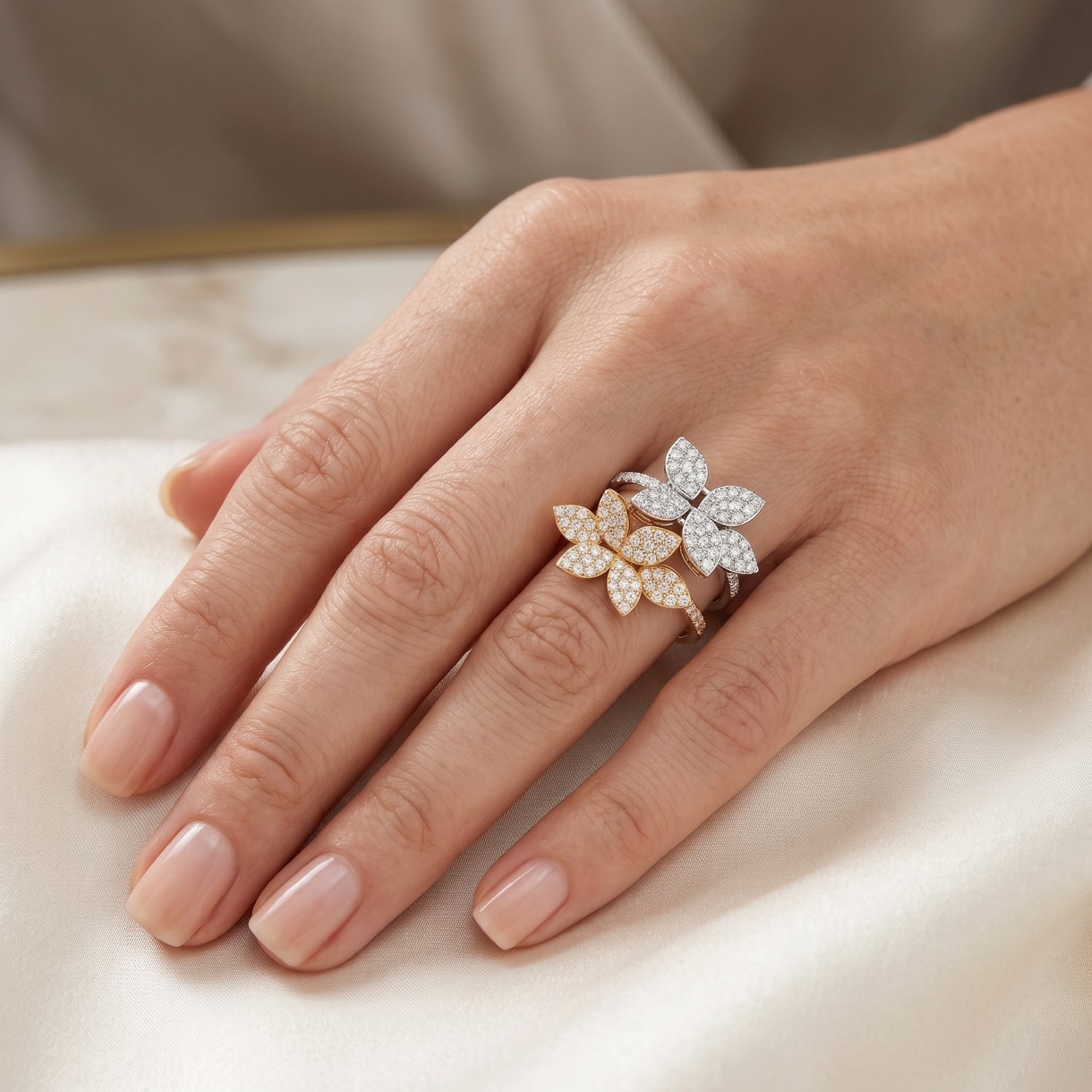 Hand wearing a decorative floral ring on a neutral background