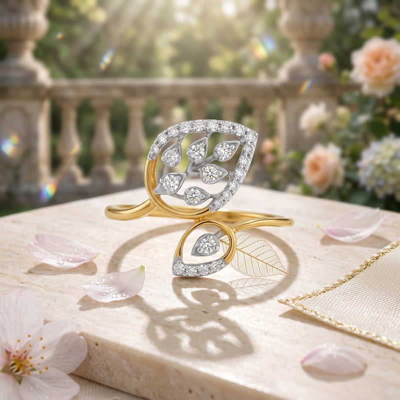 Gold and silver leaf-shaped rings on a stone surface with flowers in the background