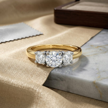 Gold ring with three diamonds on a marble surface
