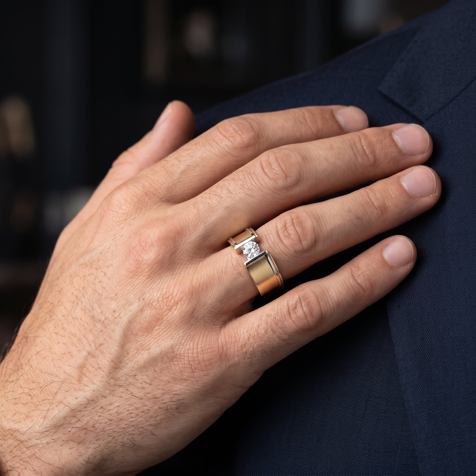 Hand wearing a gold ring with a diamond on a dark background