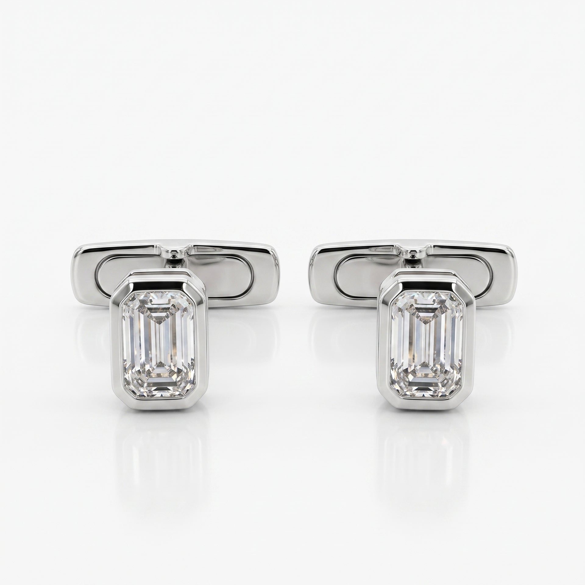 A pair of silver-toned cufflinks, each featuring an emerald-cut clear gemstone in a polished rectangular setting, displayed on a clean white reflective surface.