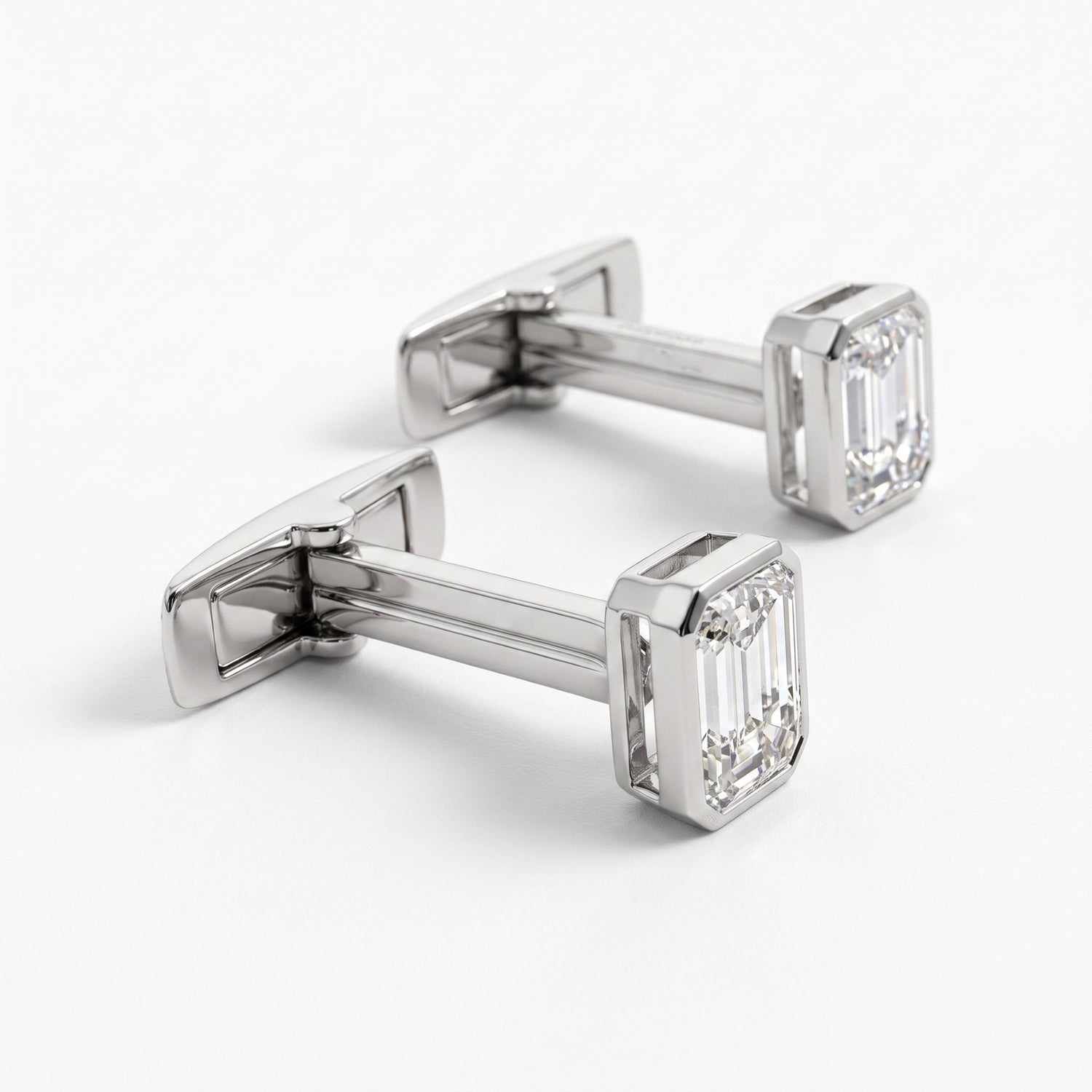 A pair of silver-toned cufflinks with rectangular emerald-cut clear gemstones, displayed on a clean white background.