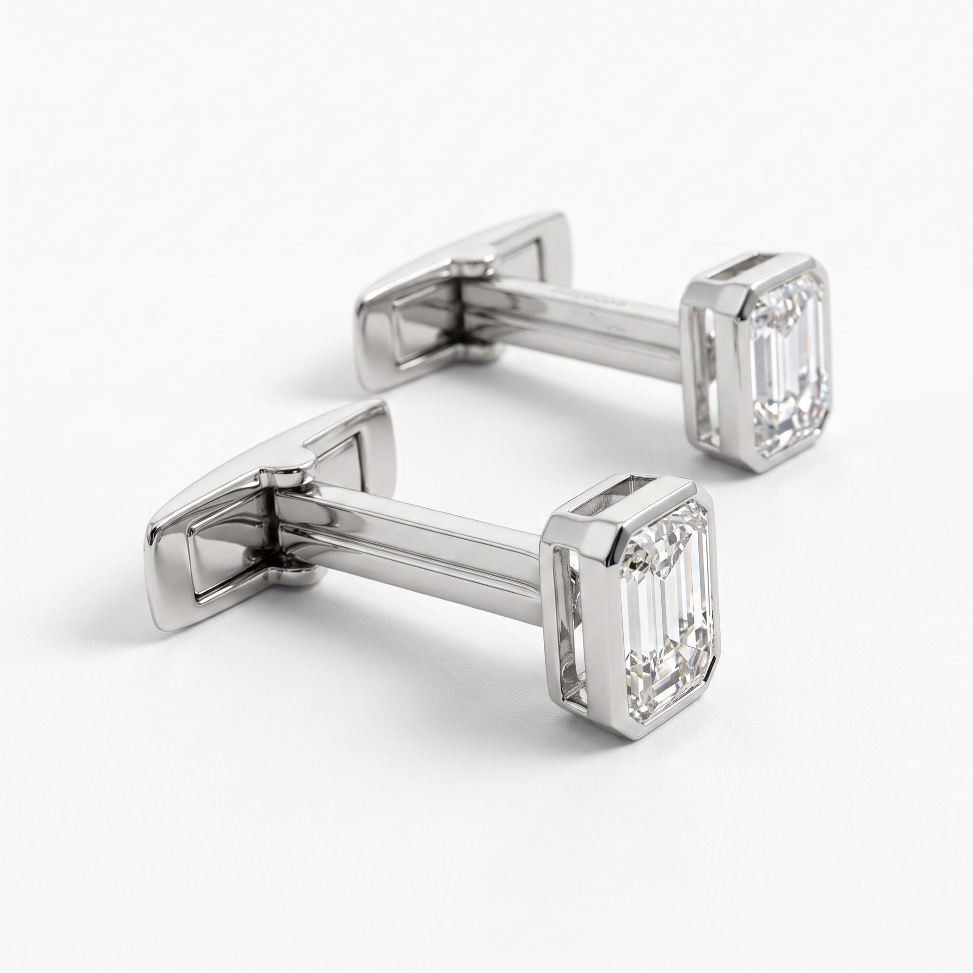 A pair of silver-toned cufflinks with rectangular emerald-cut clear gemstones, displayed on a clean white background.