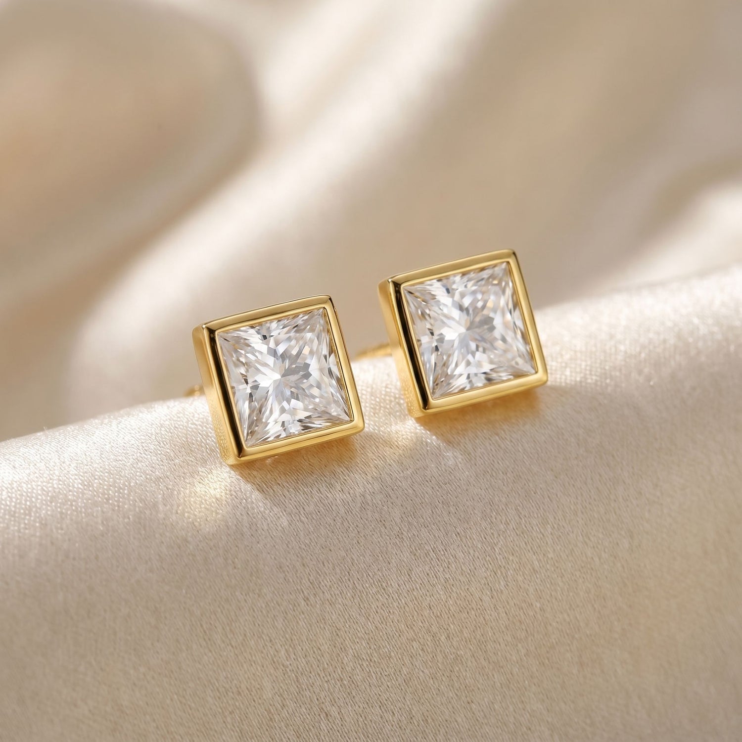 Gold square-cut stud earrings with square shaped diamond in the centre on a soft beige background