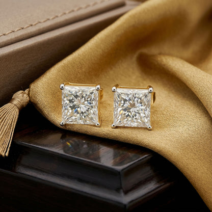 Pair of diamond stud earrings on a textured surface with a beige fabric background