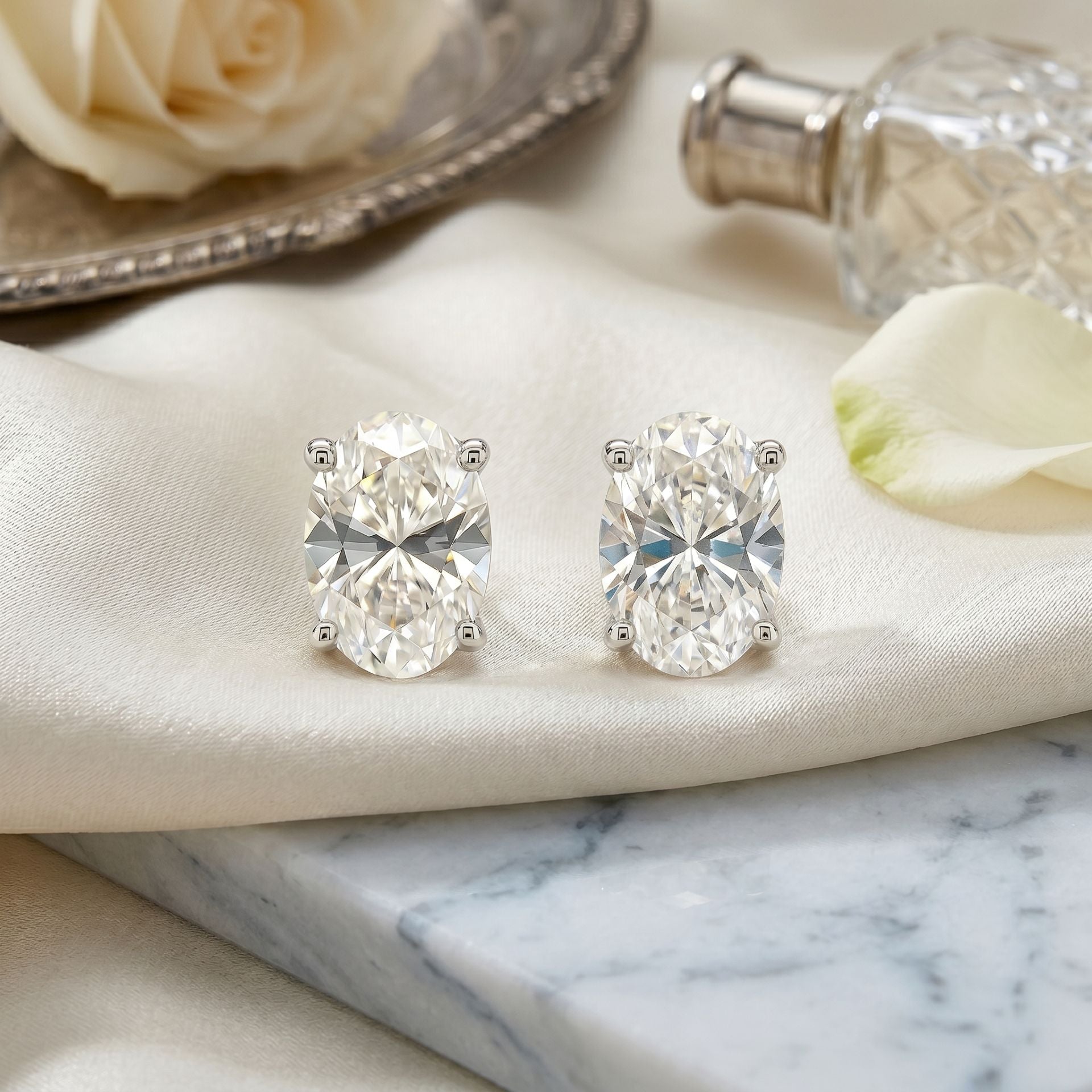 Diamond earrings on a marble surface with flowers in the background