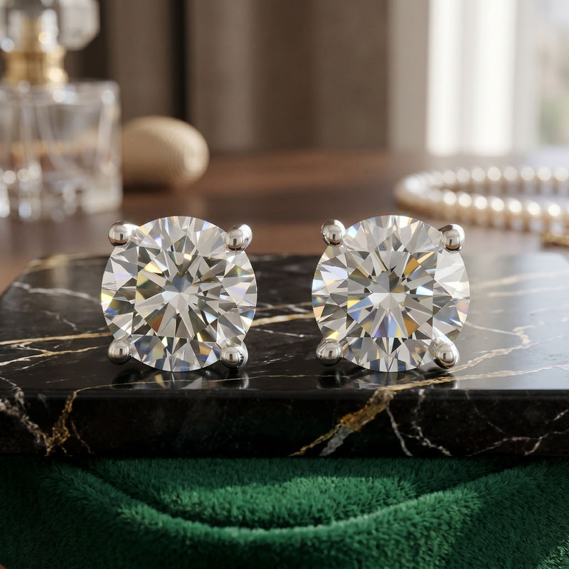Diamond stud earrings on a black marble surface with a blurred background