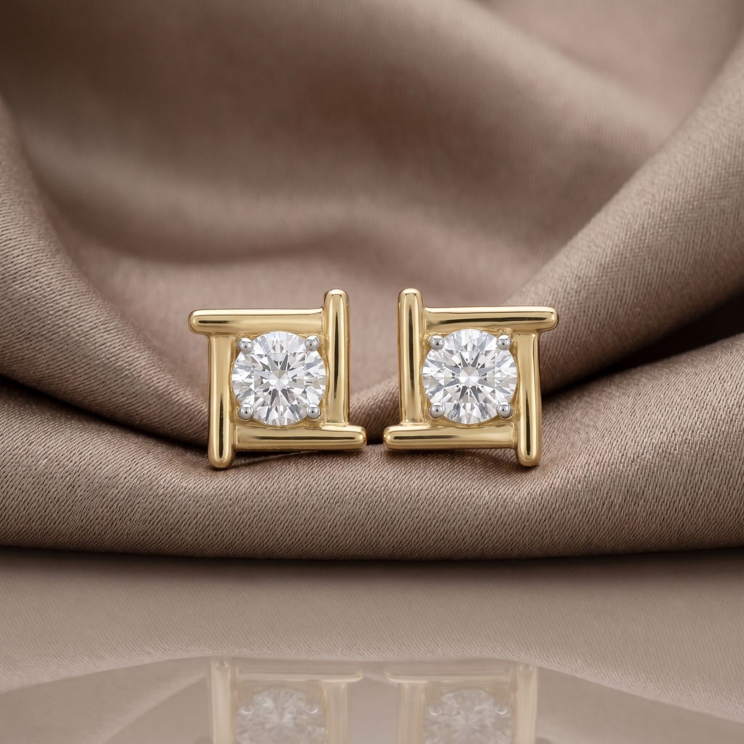 Gold halo lab grown diamond stud earrings on a beige satin background