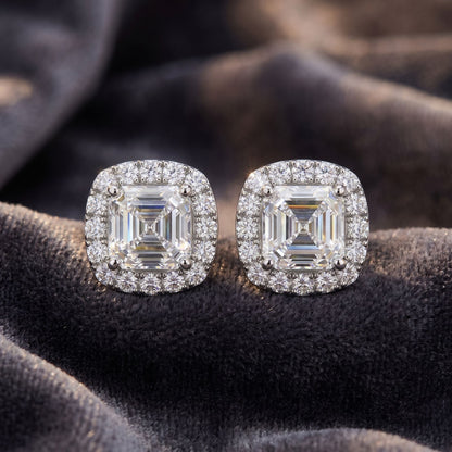 Pair of diamond earrings on a dark fabric background