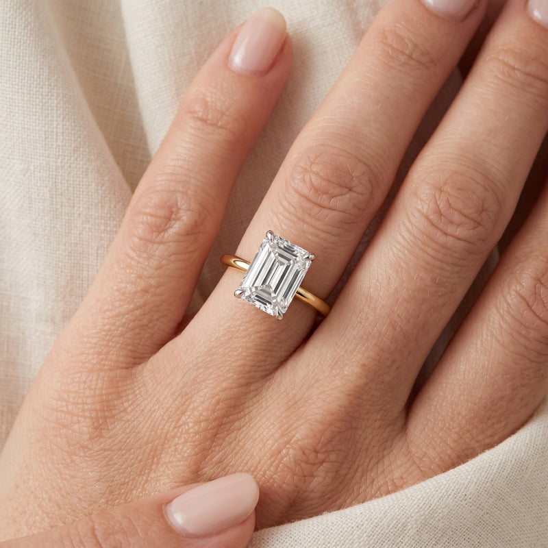 Gold ring with a diamond on a hand against a beige fabric background