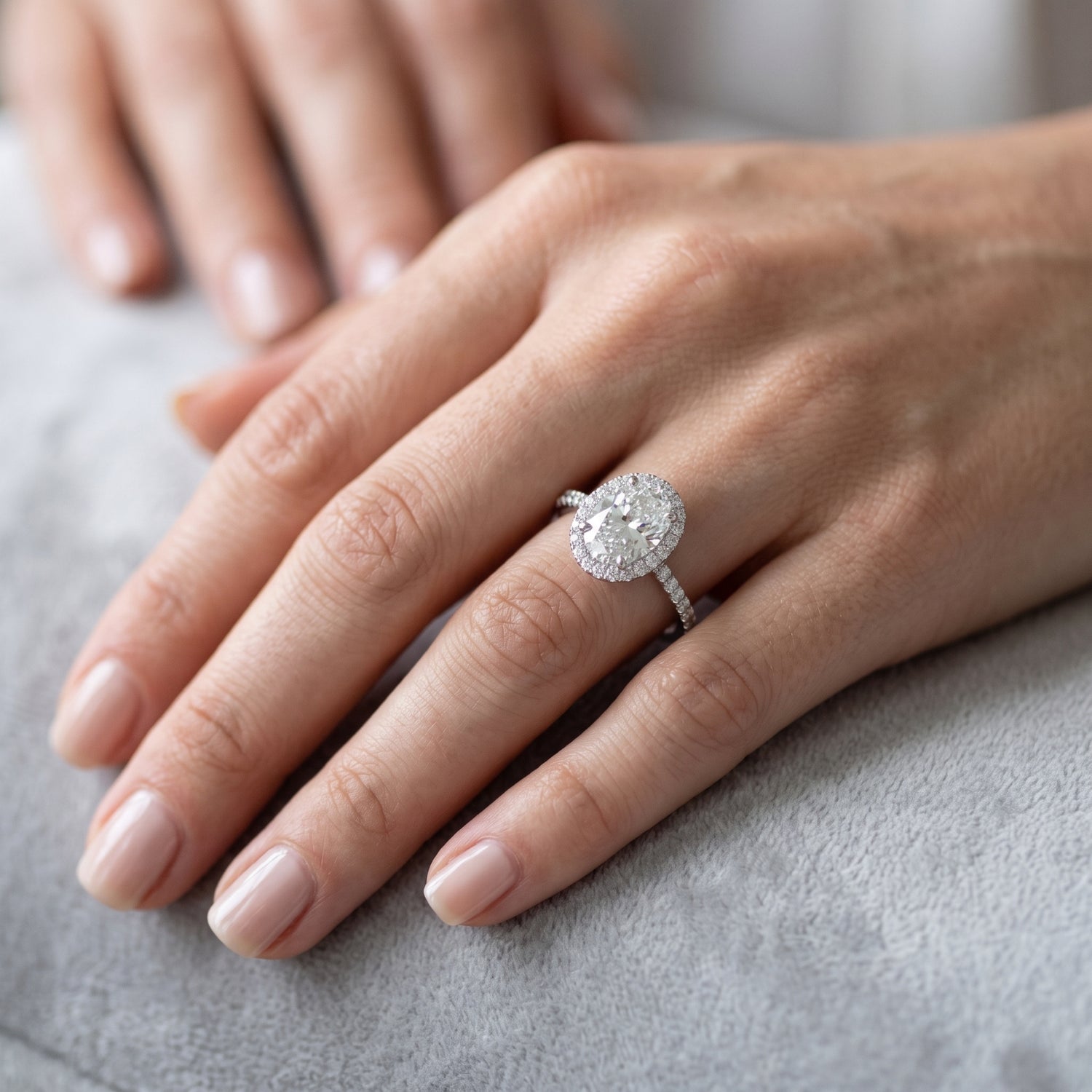 Close-up of a hand wearing a diamond ring on a neutral background