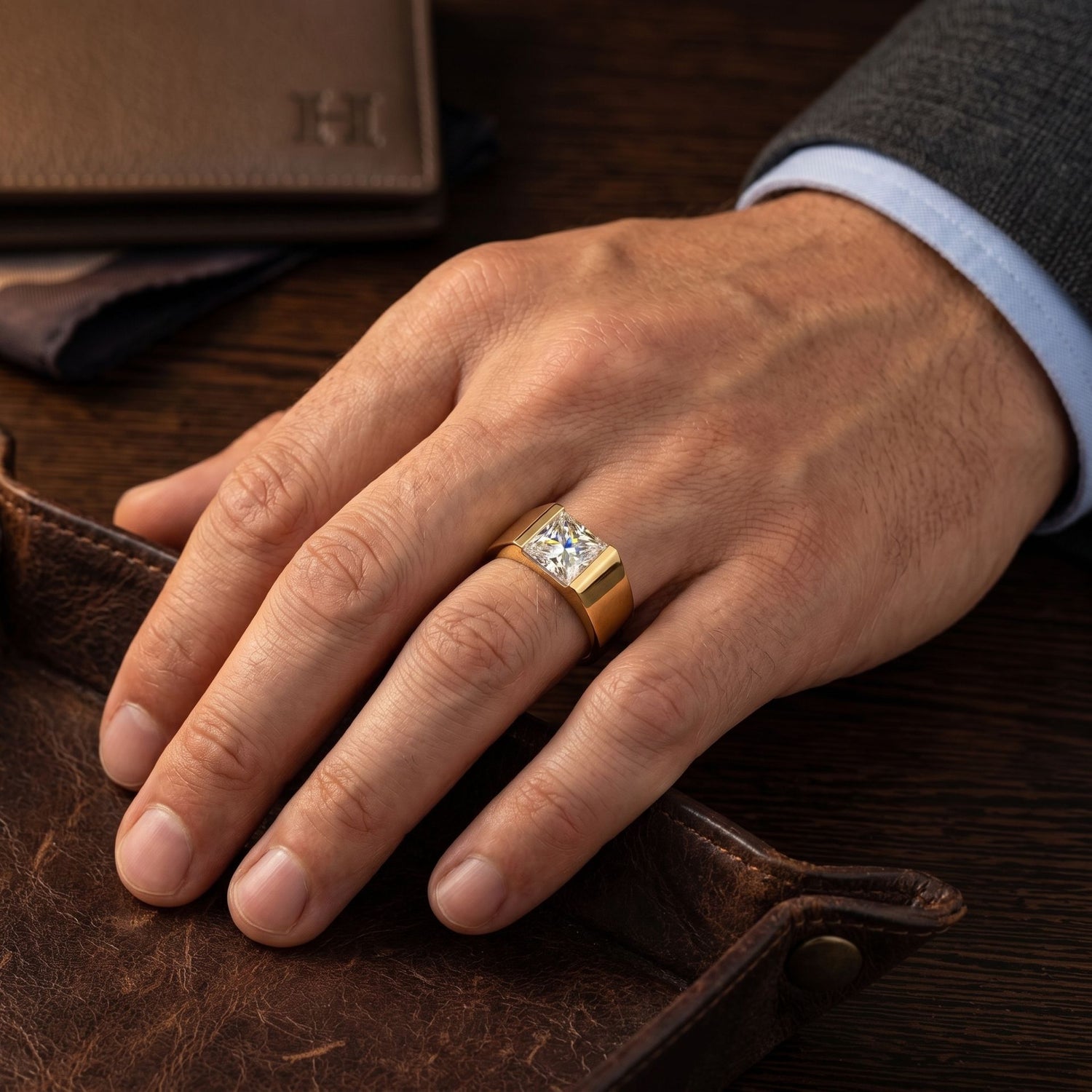 Hand wearing a gold ring with a diamond on a brown leather surface