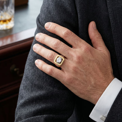 Hand wearing a gold ring with a diamond, resting on a gray suit jacket.