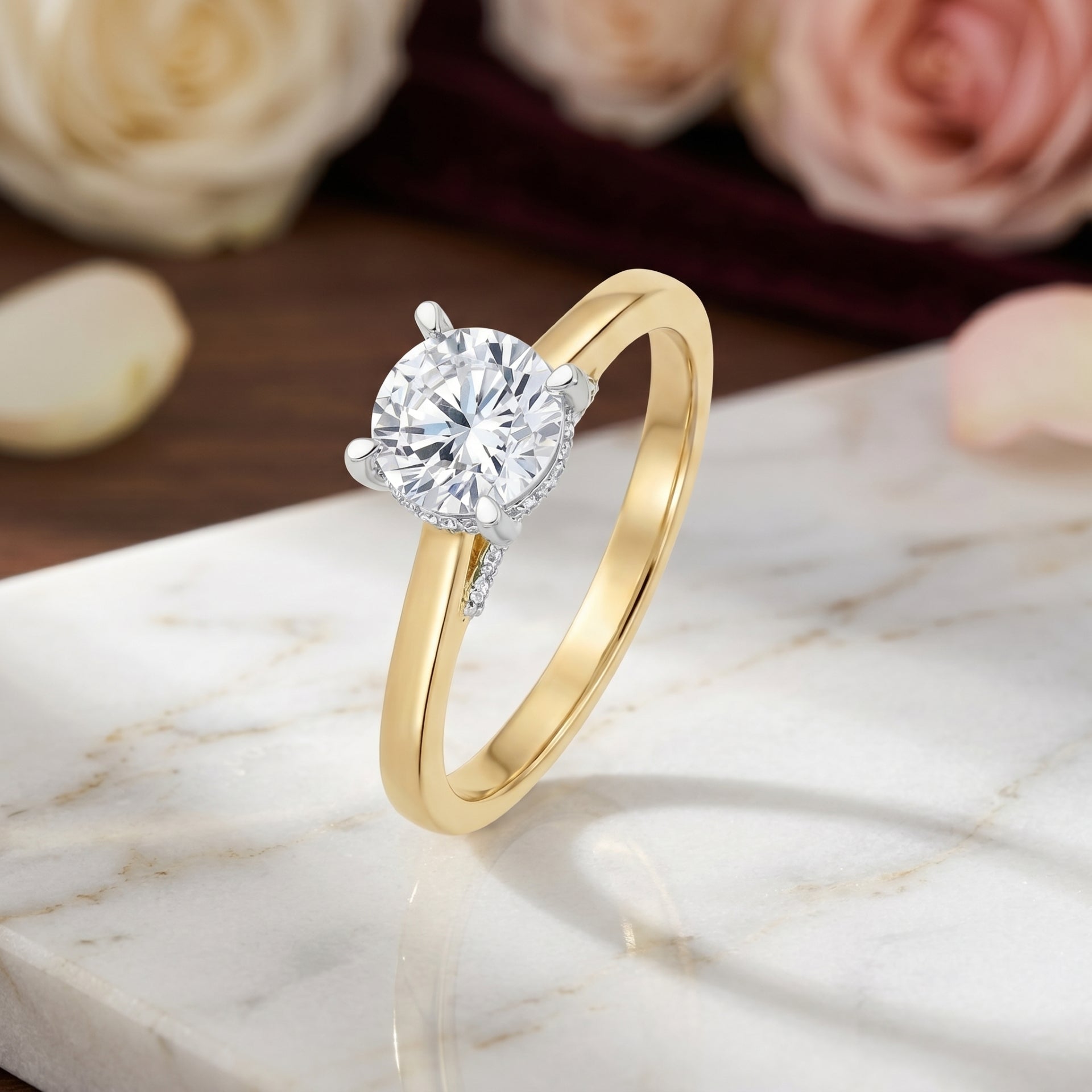 Gold ring with a diamond on a marble surface with flowers in the background