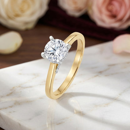 Gold ring with a diamond on a marble surface with flowers in the background