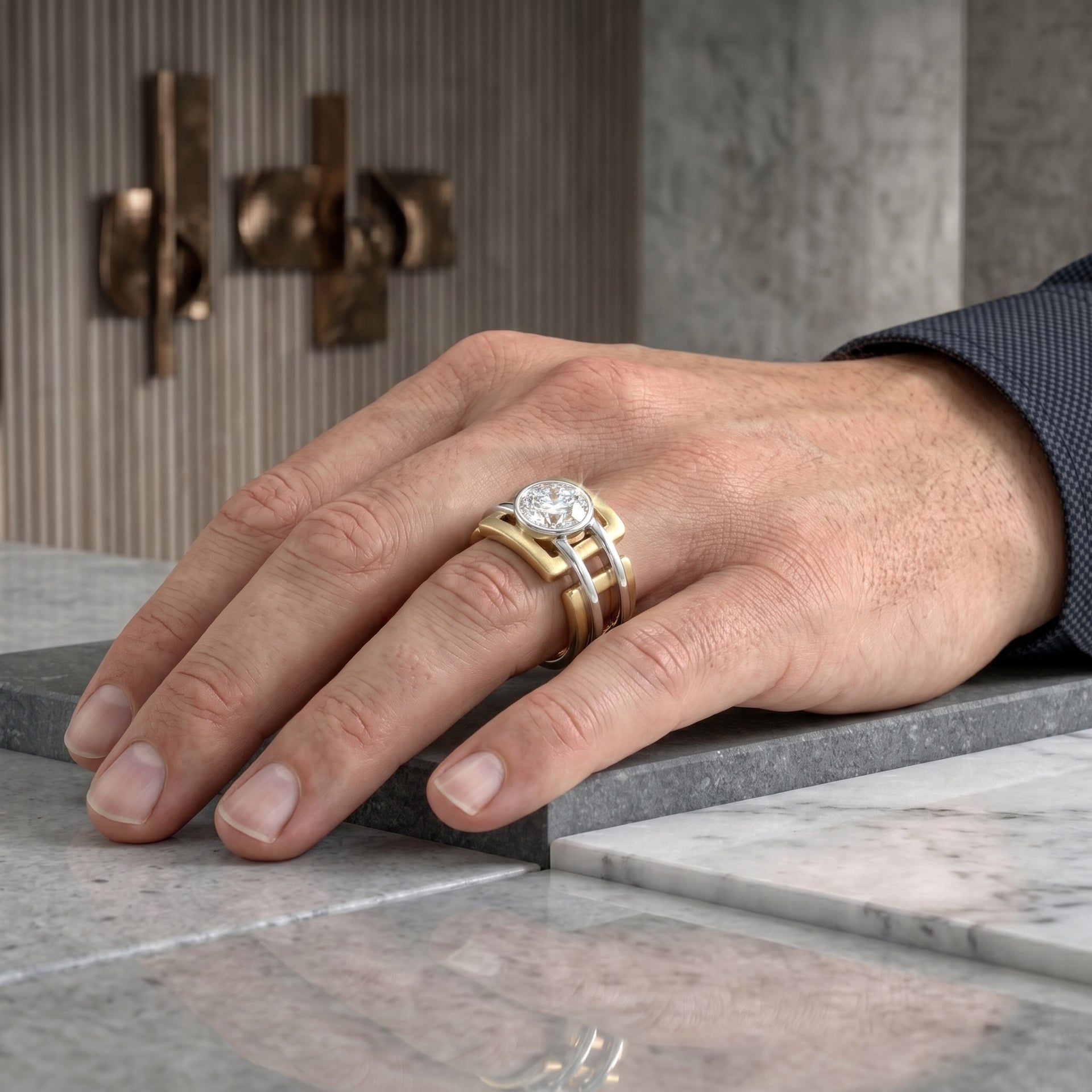 Hand wearing a gold and silver ring on a marble surface with a blurred background