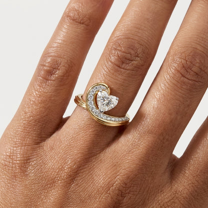 Gold ring with a heart-shaped diamond on a hand against a white background