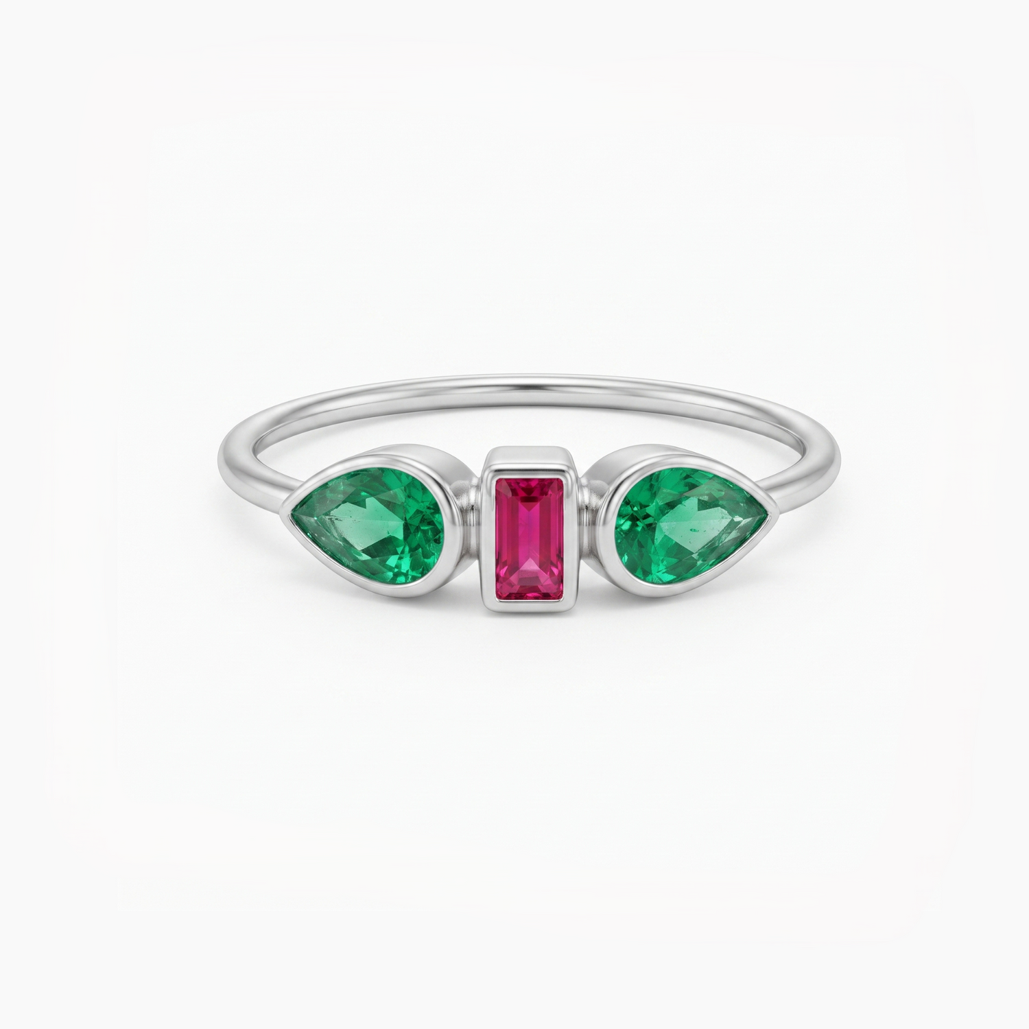 A silver ring featuring two green marquise-cut gemstones on either side of a central rectangular pink gemstone, set against a plain white background.