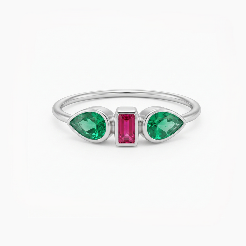 A silver ring featuring two green marquise-cut gemstones on either side of a central rectangular pink gemstone, set against a plain white background.