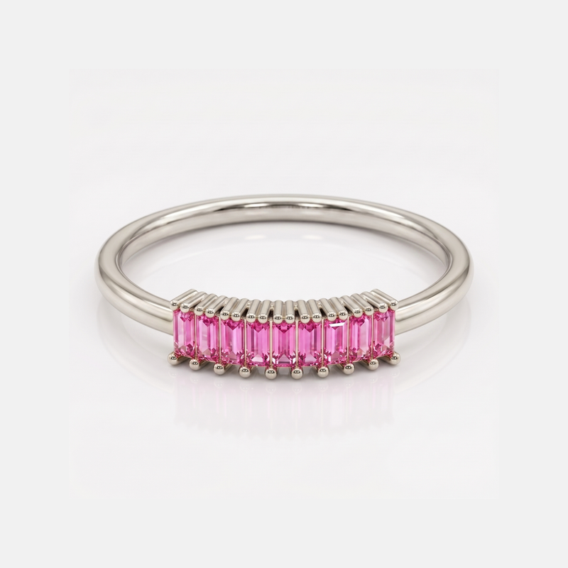 A silver band ring featuring a curved row of baguette-cut pink gemstones in a prong setting, shown on a clean white background.