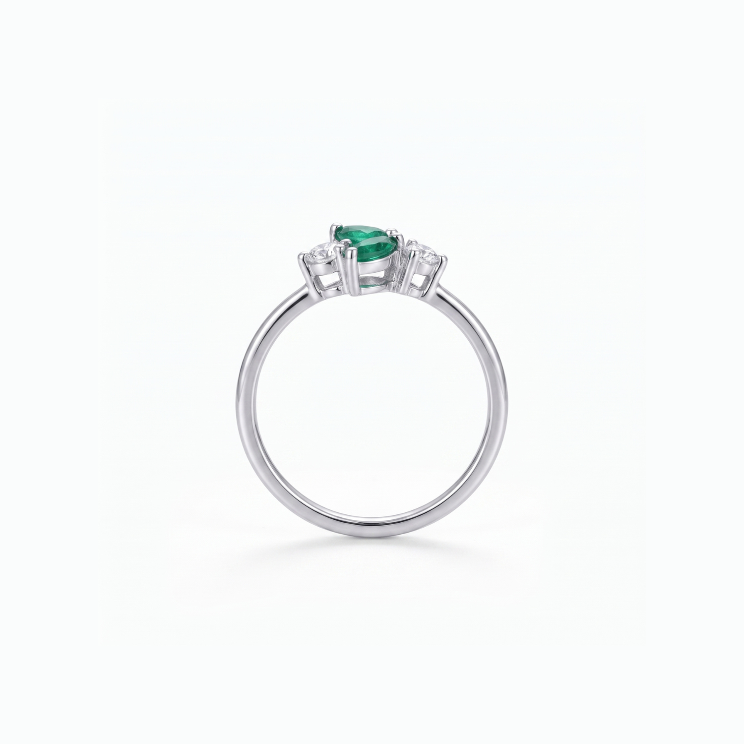 A silver ring featuring a pear-cut green emerald center stone and small clear accent stones on either side, shown on a clean white background.