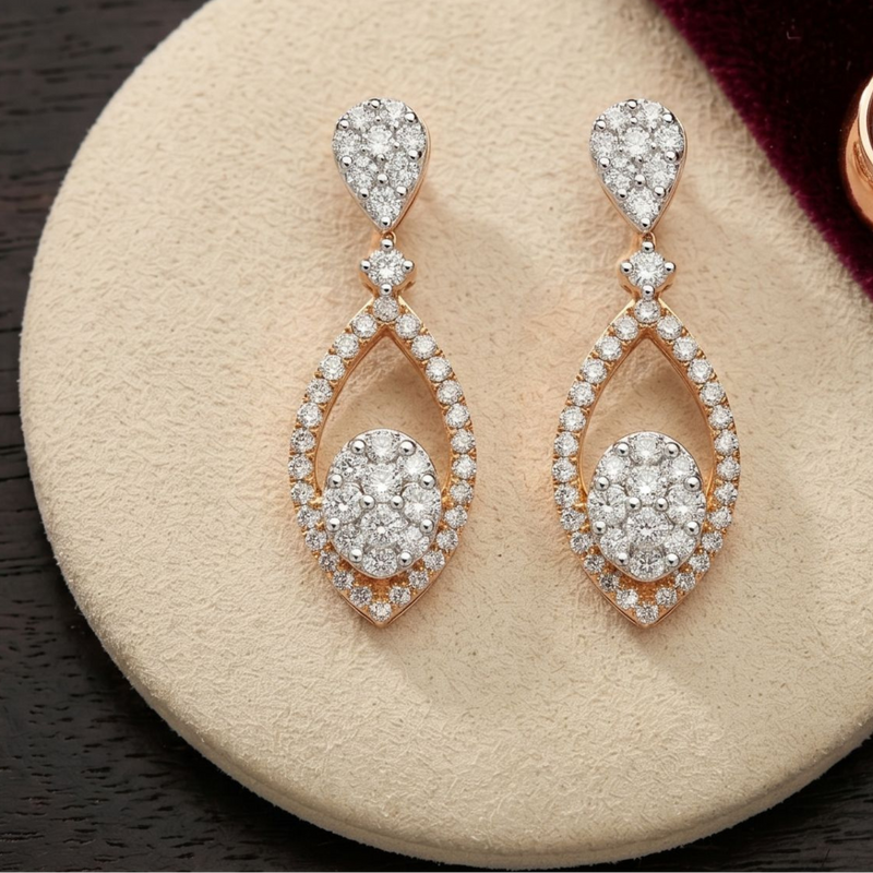 Rose gold drop earrings with clear pavé stones, displayed on a round beige jewelry stand with a dark wood surface and a burgundy velvet cloth.