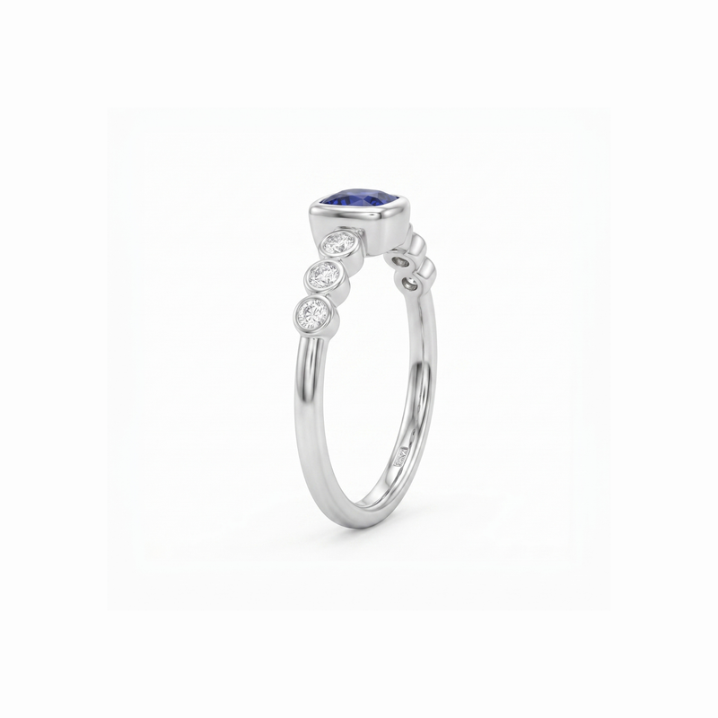 A silver ring featuring a marquise-cut blue sapphire center stone and three small round-cut clear stones along the shank, shown on a plain white background.