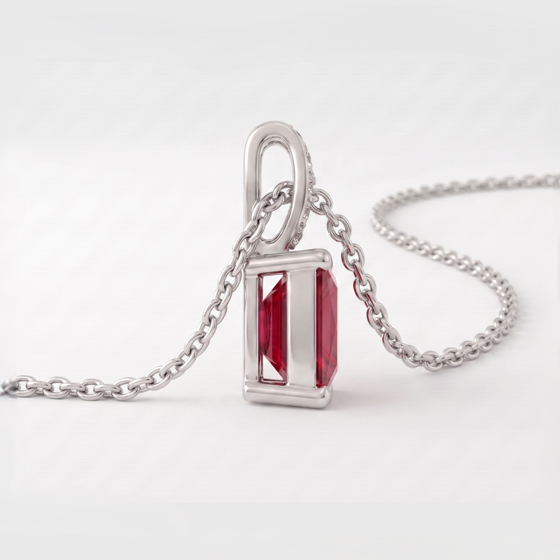 A silver pendant necklace featuring a rectangular red gemstone in a polished silver bezel setting, suspended from a silver chain on a light gray background.