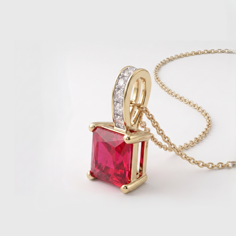 A gold pendant necklace featuring a square-cut red gemstone and a curved bail set with small clear stones, shown on a light gray background.