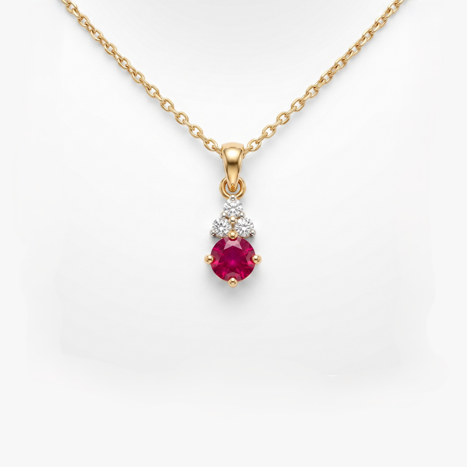 A gold pendant necklace featuring a round-cut pinkish-red ruby gemstone and a small cluster of clear stones above it, shown on a white background.