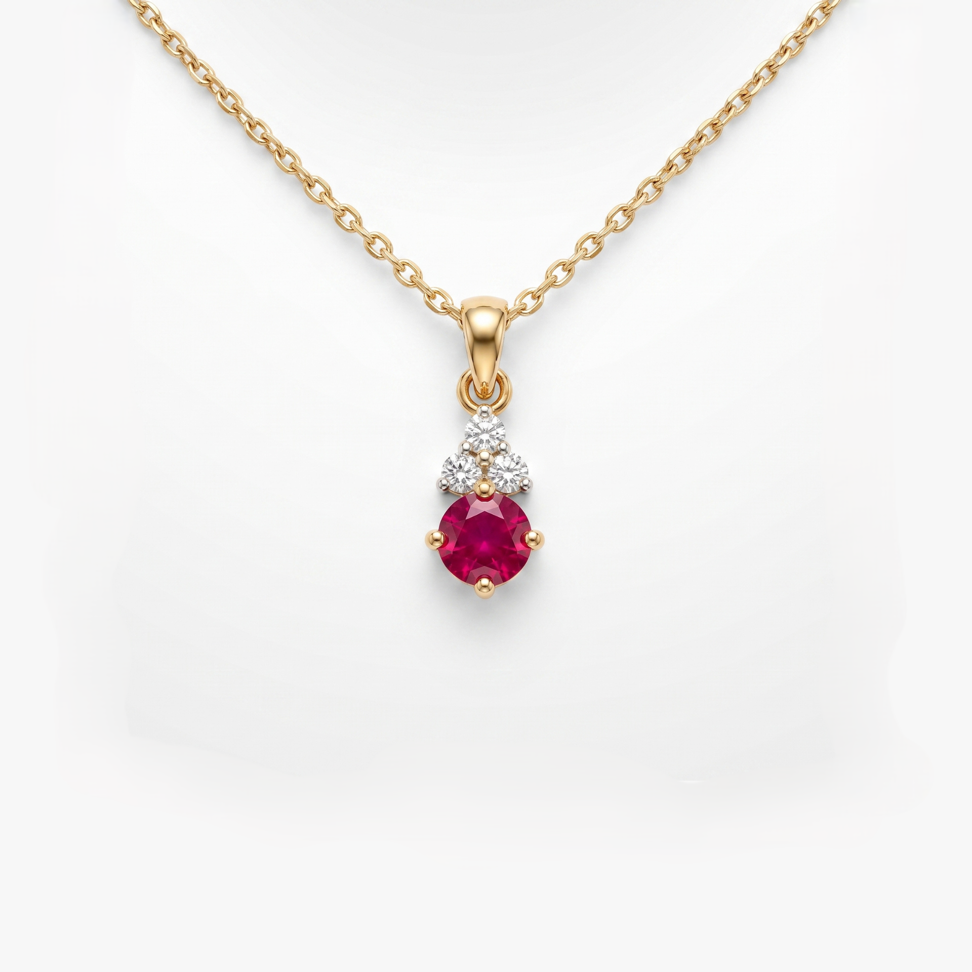 A gold pendant necklace featuring a round-cut pinkish-red ruby gemstone and a small cluster of clear stones above it, shown on a white background.