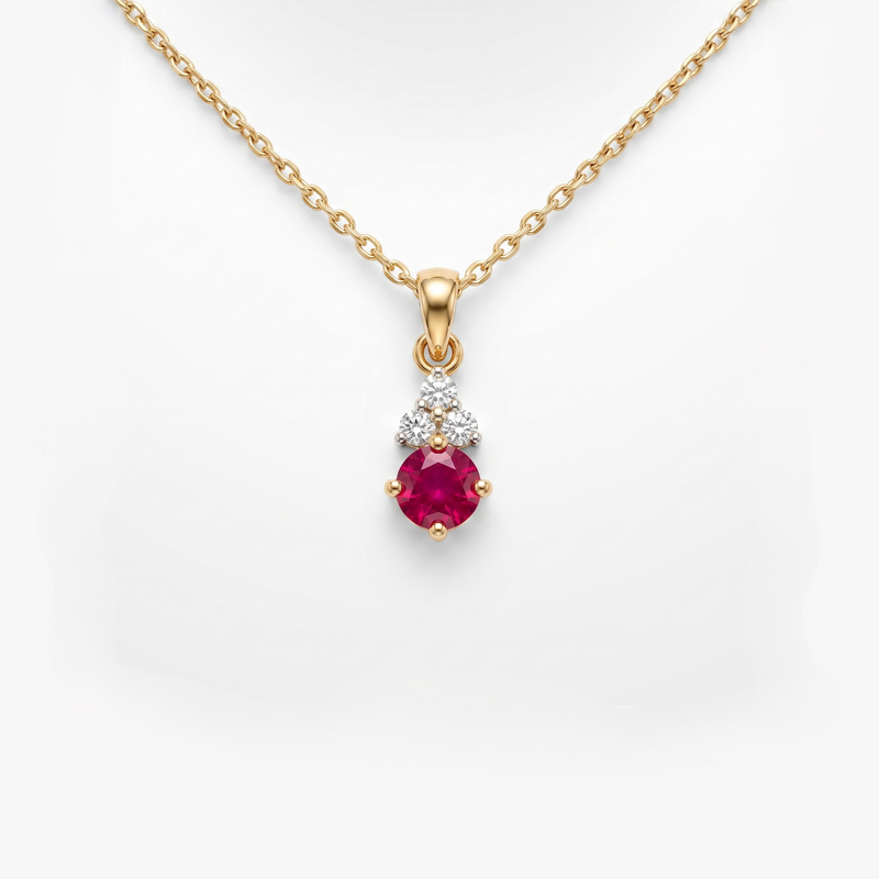 A gold pendant necklace featuring a round-cut pinkish-red ruby gemstone and a small cluster of clear stones above it, shown on a white background.