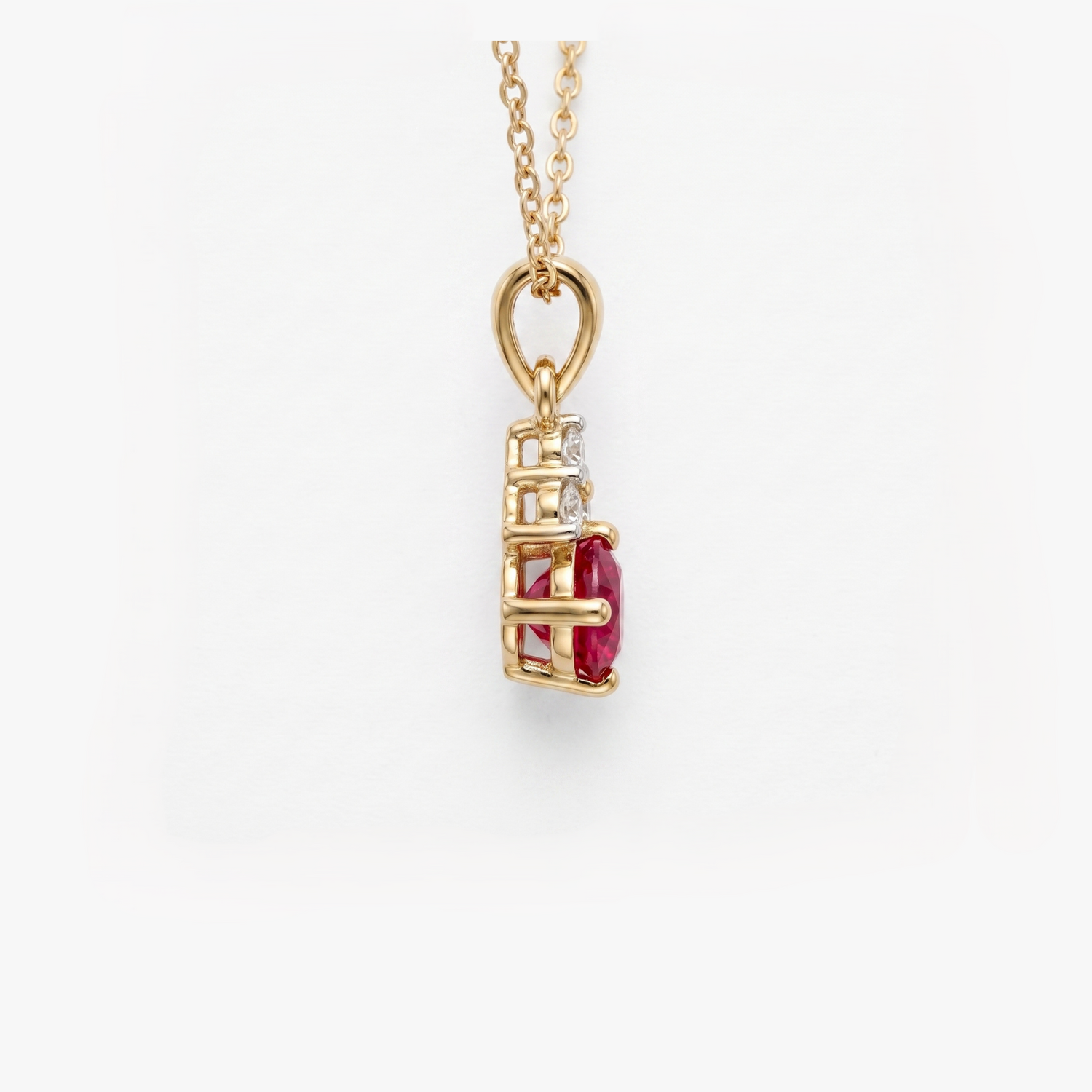 A gold pendant necklace featuring a vertical setting with a prominent oval-cut red ruby center stone and a small clear diamond beside it, suspended from a delicate gold chain against a clean white background.