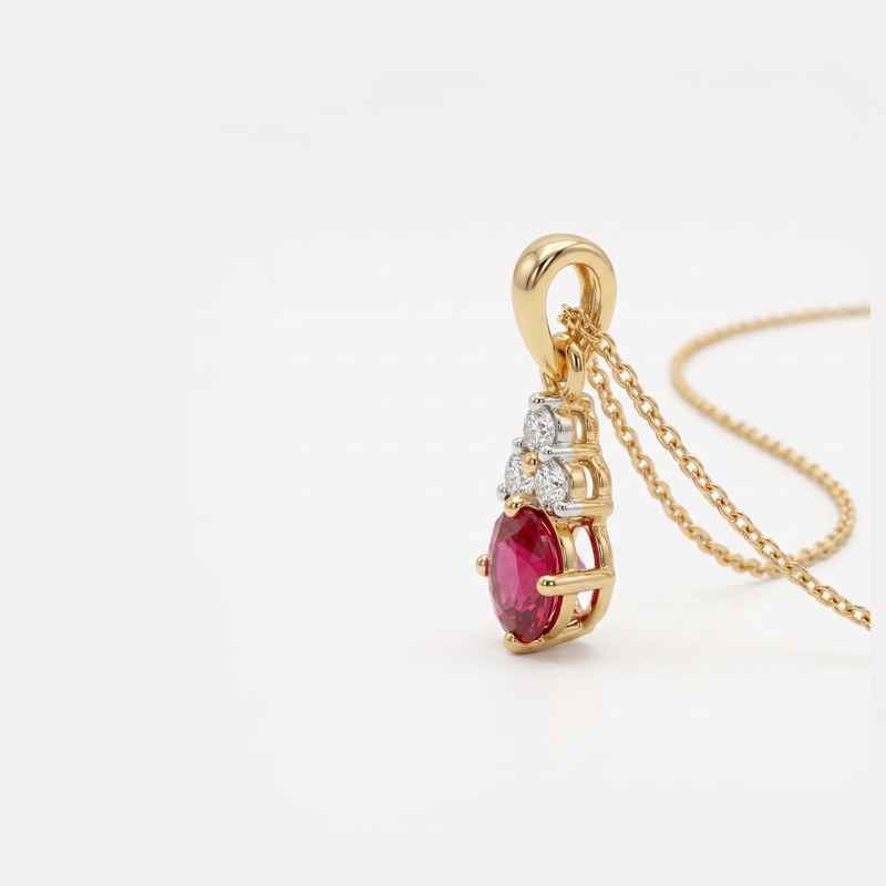 A gold pendant necklace featuring a teardrop-shaped pinkish-red gemstone and small clear accent stones, shown on a plain white background.