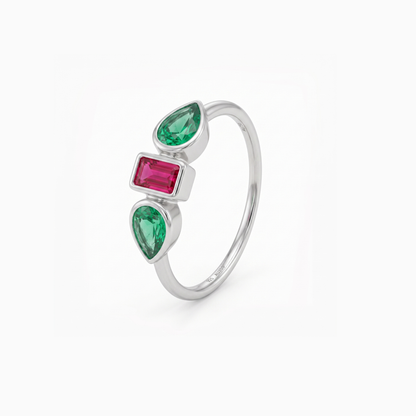 A silver ring featuring three vertically aligned gemstones: two pear-cut emerald-cut green stones and one rectangular emerald-cut pink stone, set in a polished silver band against a clean white background.