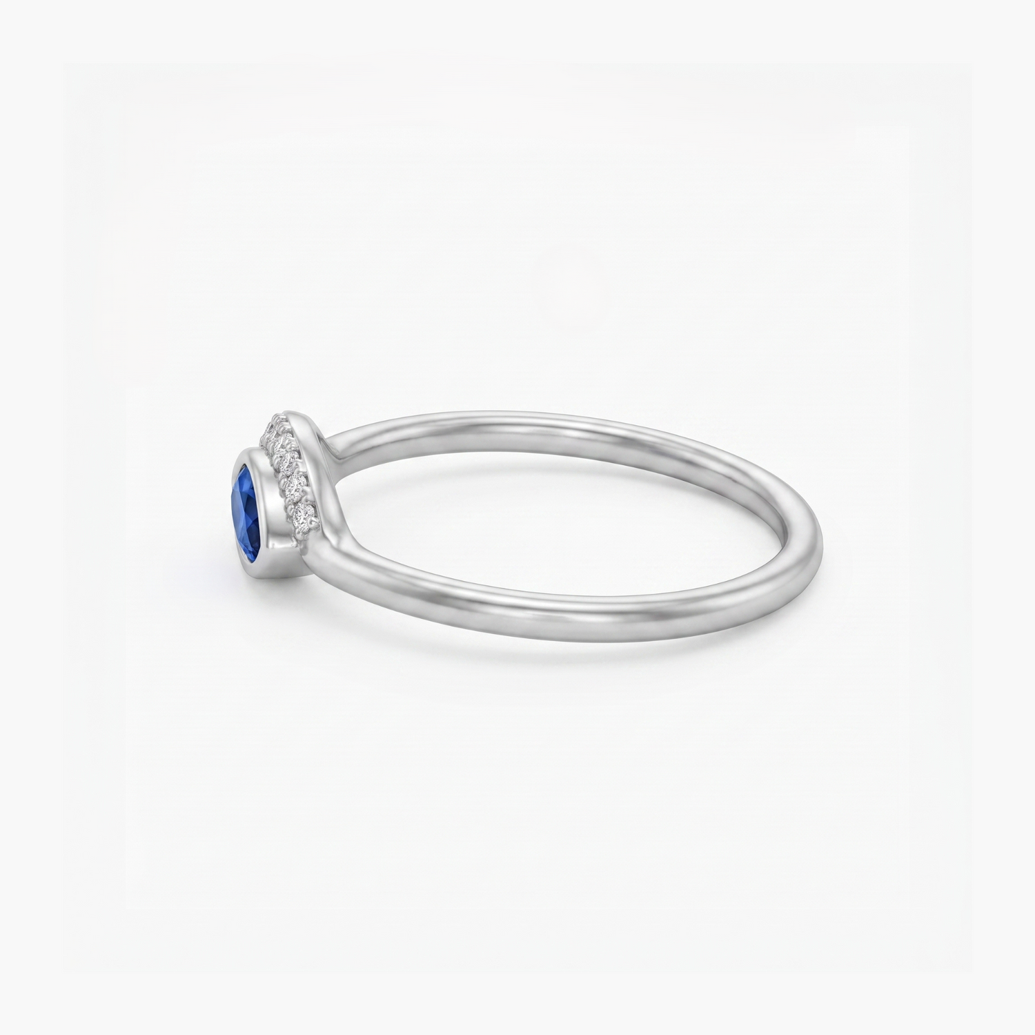 A silver ring featuring a round-cut blue sapphire center stone and a halo of small clear stones along the shank, shown on a clean white background.